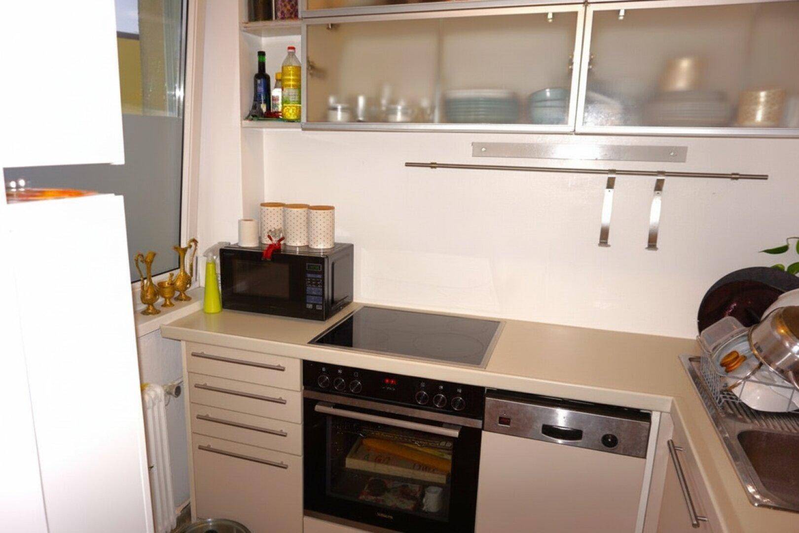 Kompakte Küche mit Einbaugeräten, Induktionskochfeld und praktischem Stauraum.