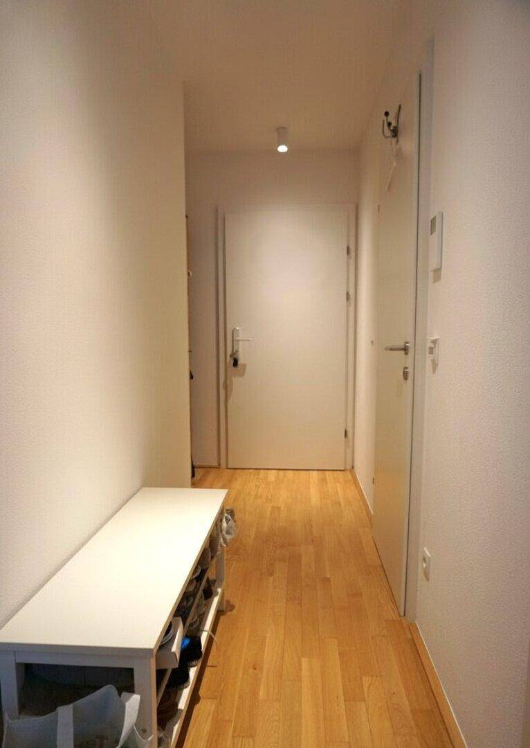 Heller Flur mit Parkettboden und einer praktischen Schuhbank, führt zu weiteren Räumen.