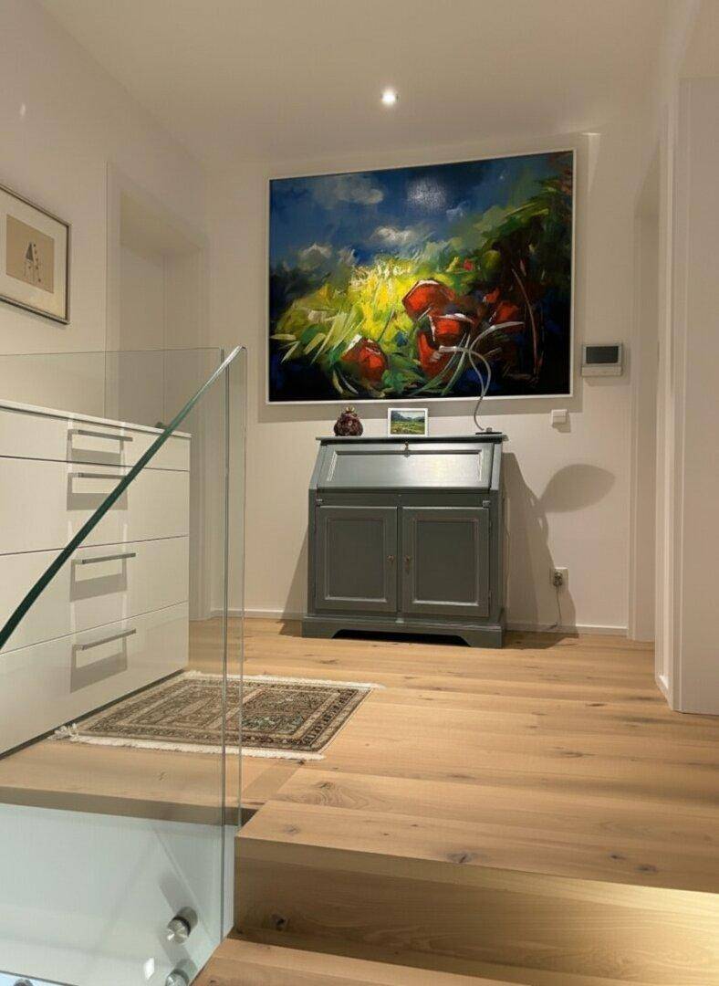 Heller Flur mit Holzboden, moderner Kunst und einem eleganten Sekretär als Blickfang.