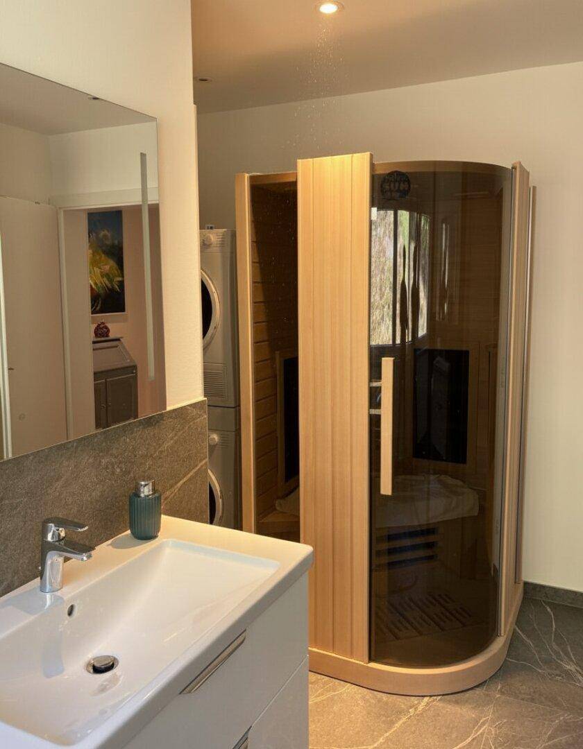 Modernes Badezimmer mit integrierter Sauna, Waschbecken und Waschmaschine/Trockner-Turm.