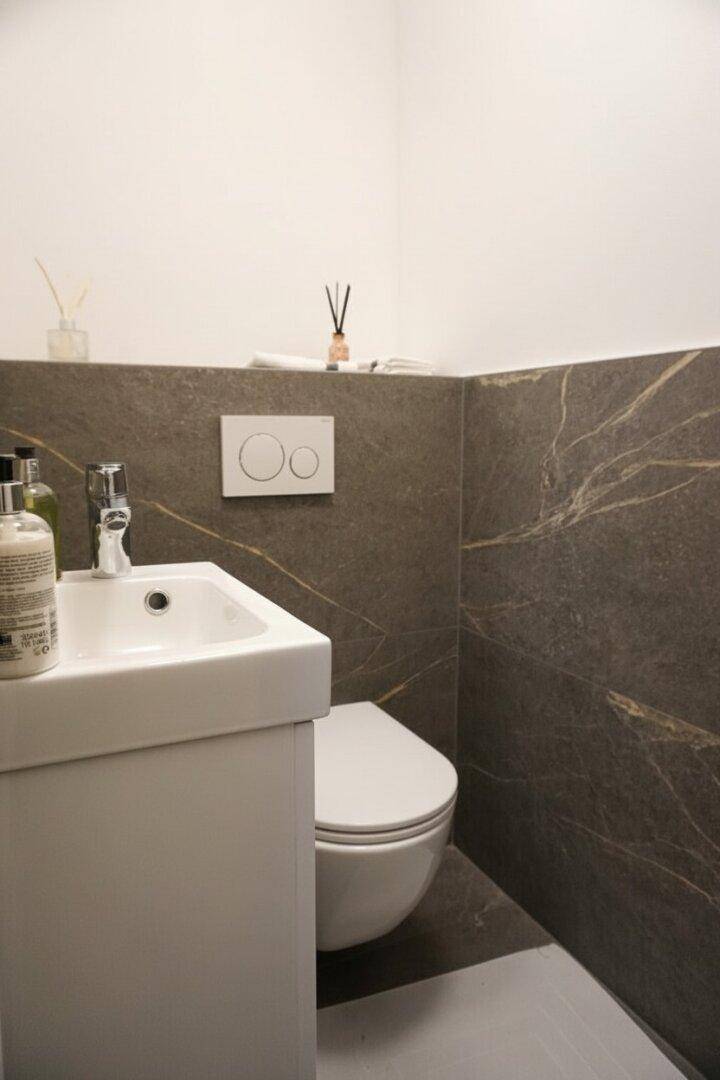 Kleines Gäste-WC mit modernem Waschbecken und wandhängender Toilette, elegant gefliest.