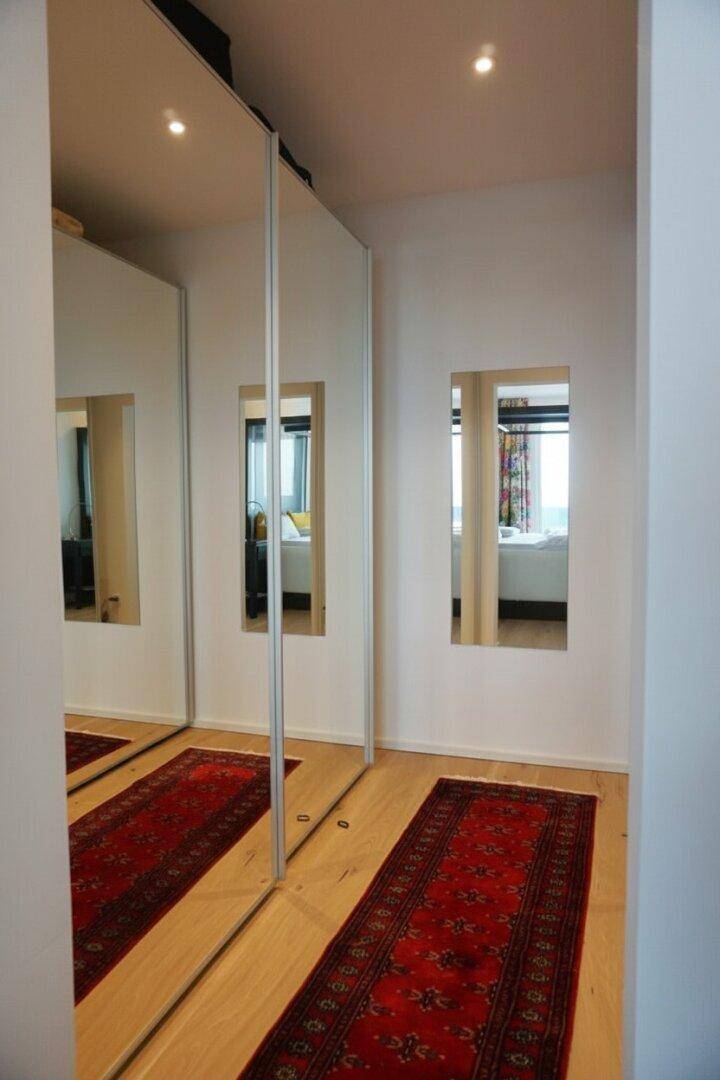 Heller Flur mit Spiegelschränken und Teppichläufer, der zu weiteren Räumen führt.