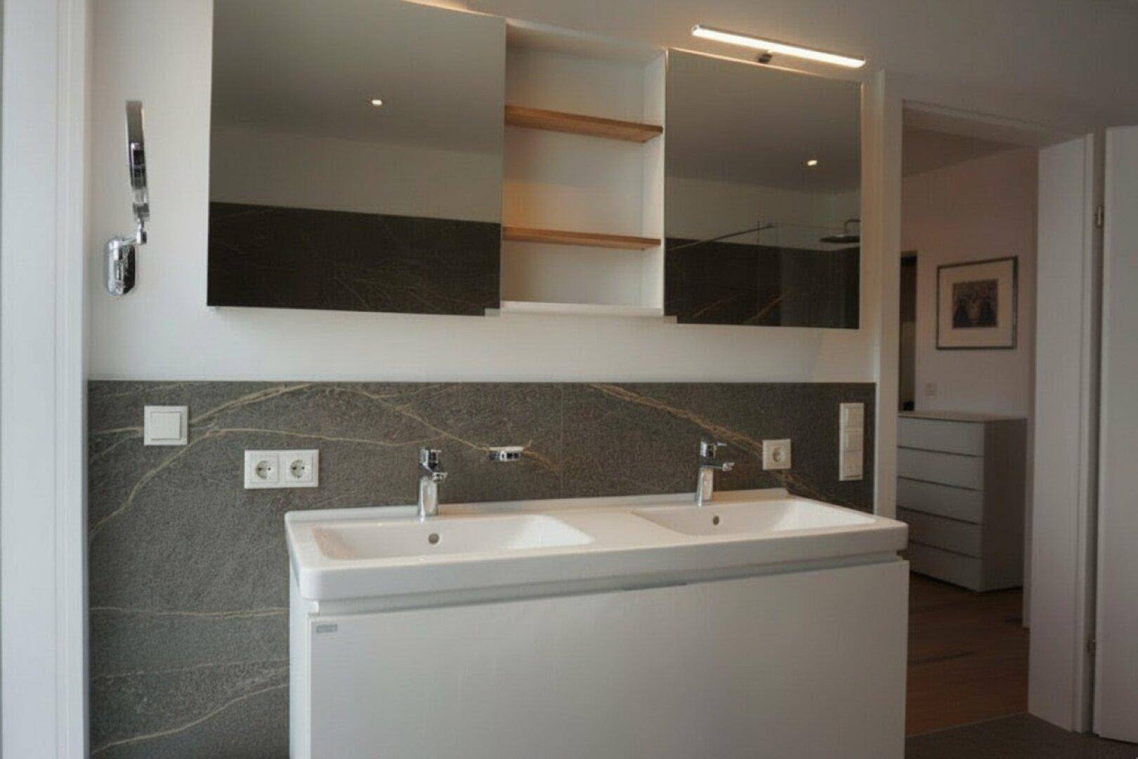 Modernes Badezimmer mit Doppelwaschbecken, Spiegelschrank und stilvollen Fliesen.