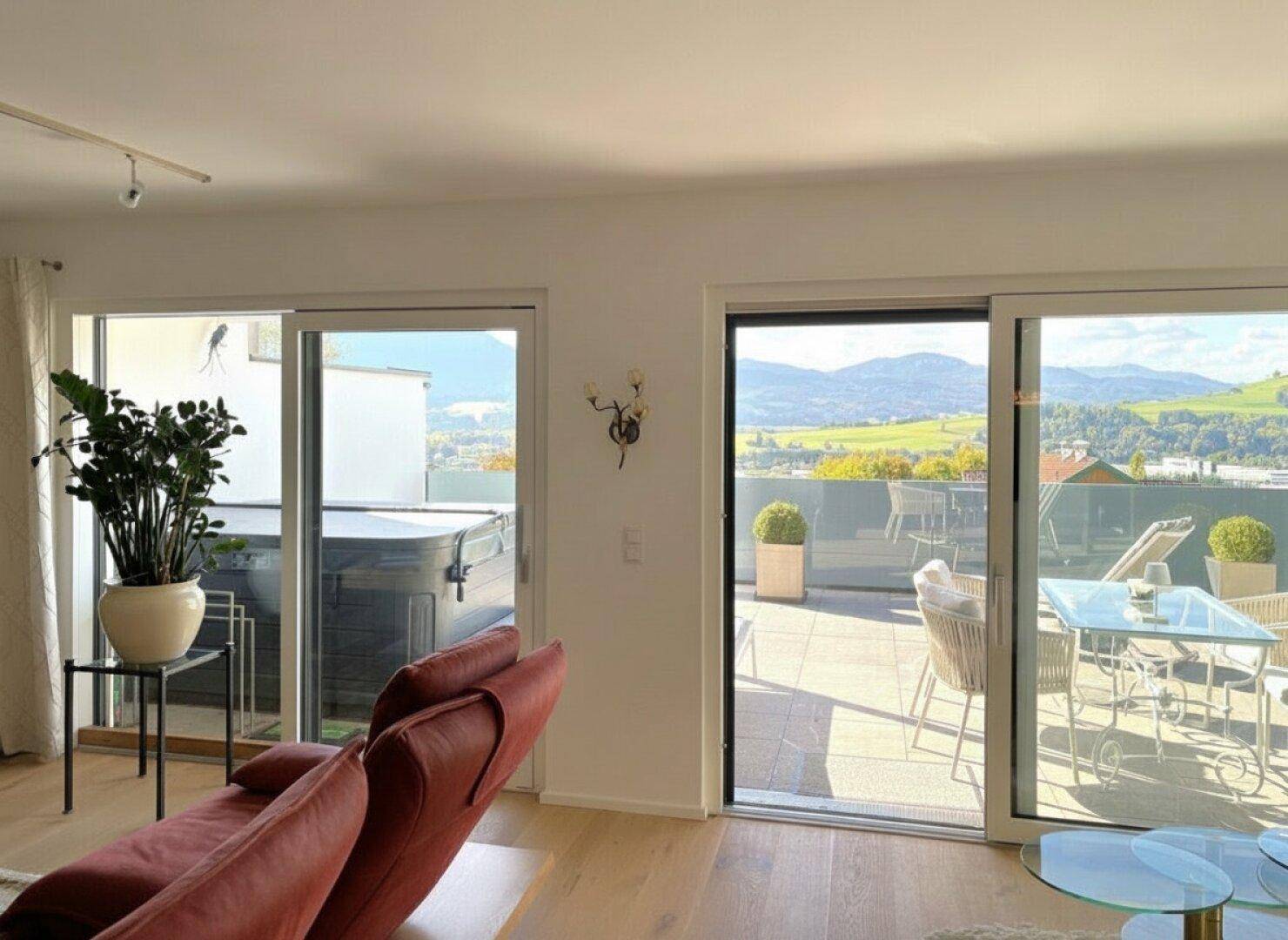 Helles Wohnzimmer mit Zugang zur großen Terrasse, die einen Whirlpool und Bergblick bietet.