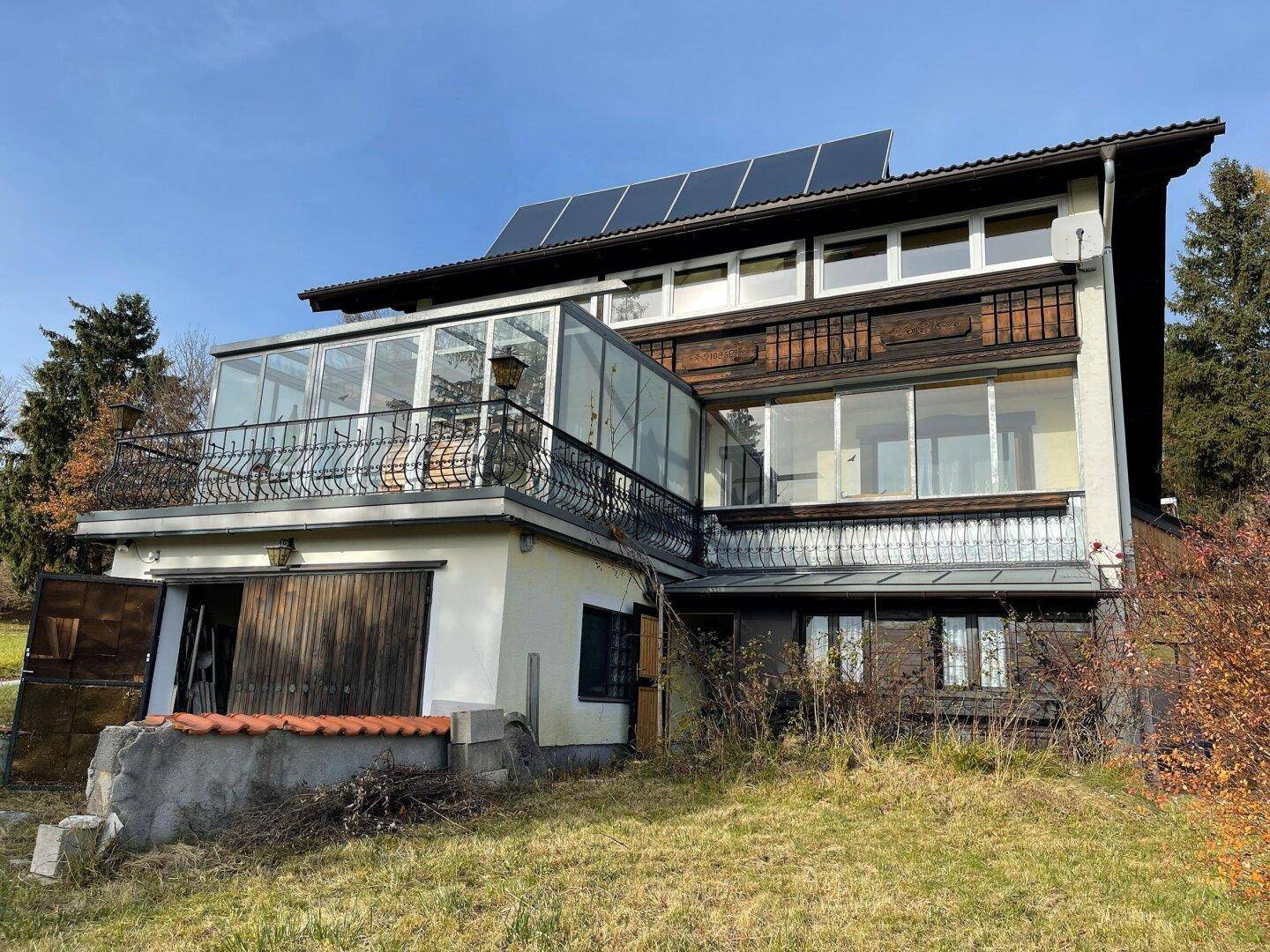 Seitenansicht des Hauses mit Wintergarten, Balkon und Solarpaneelen auf dem Dach.