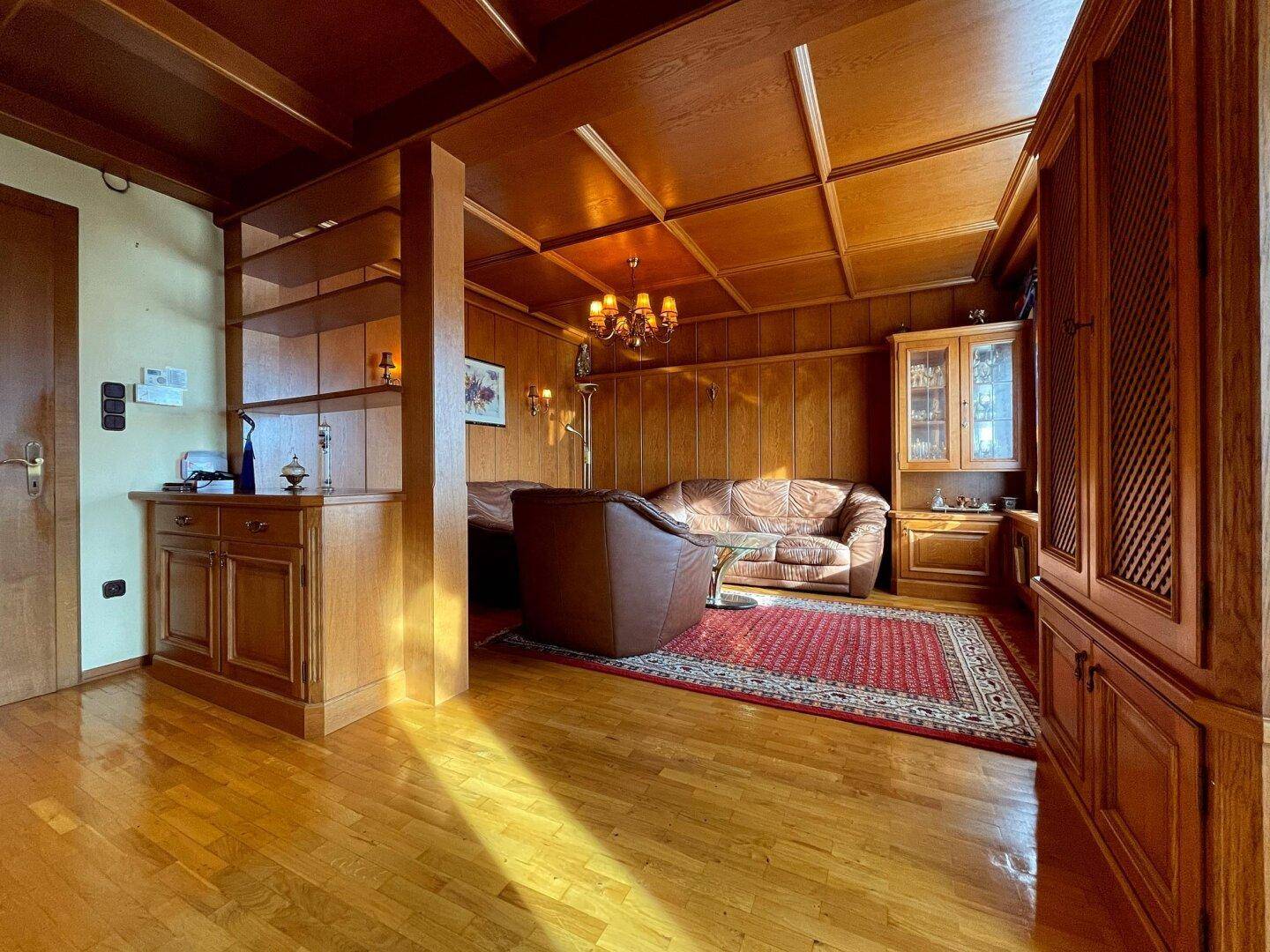 Heller Wohnbereich mit Ledersofas, Holzböden und einer Decke aus Holzpaneelen.