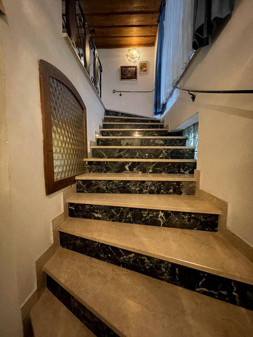 Elegante Treppe mit Marmorstufen und schmiedeeisernem Geländer, die in die obere Etage führt.