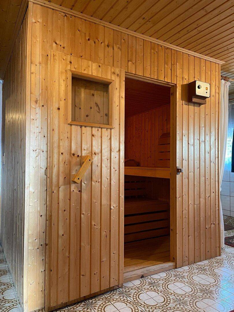 Eine holzvertäfelte Sauna mit charakteristischen Bänken und Heizofen, bereit zur Nutzung.