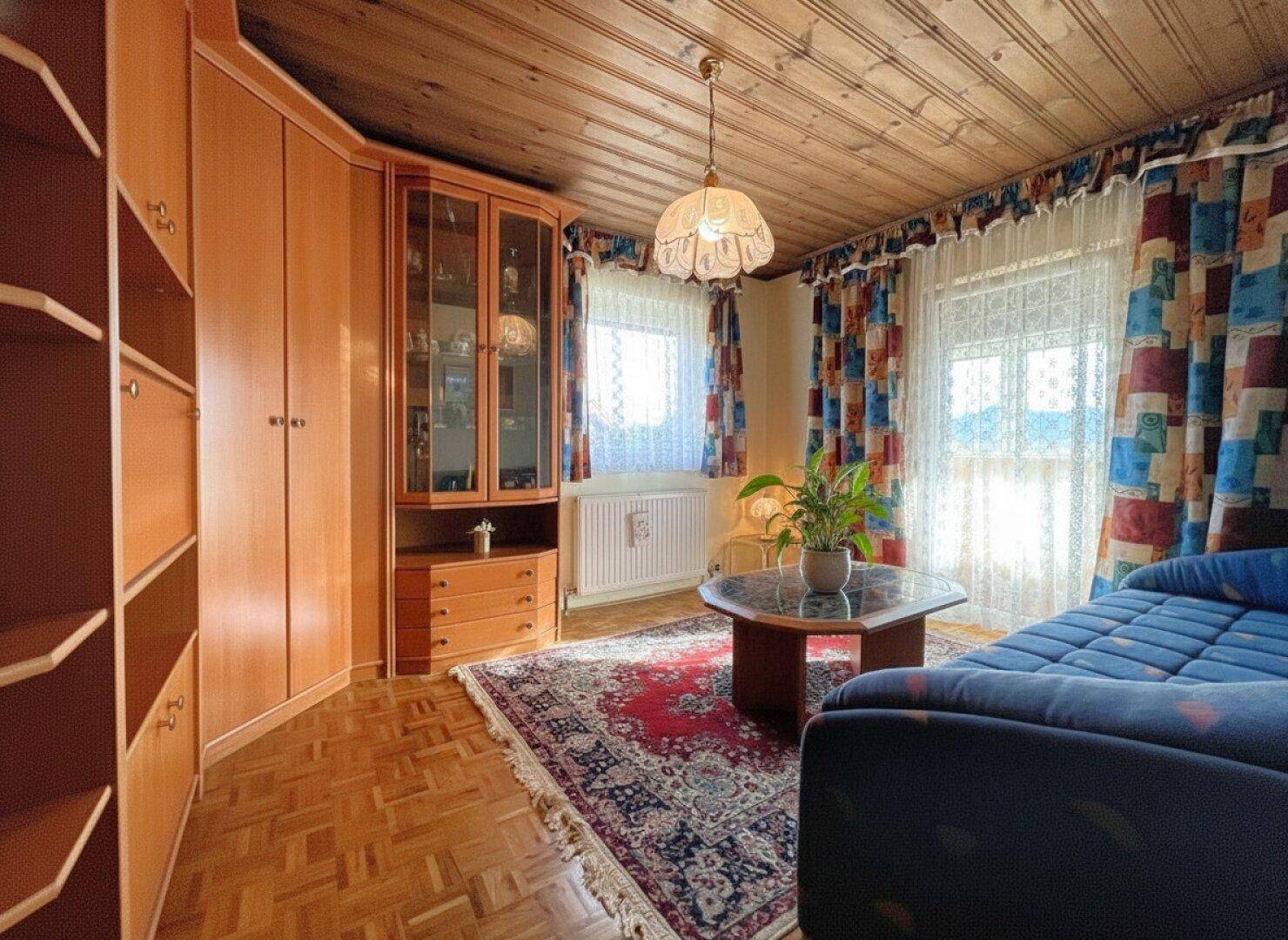Helles Zimmer mit Holzdecke, Teppichboden und einem Eckschrank, der viel Stauraum bietet.