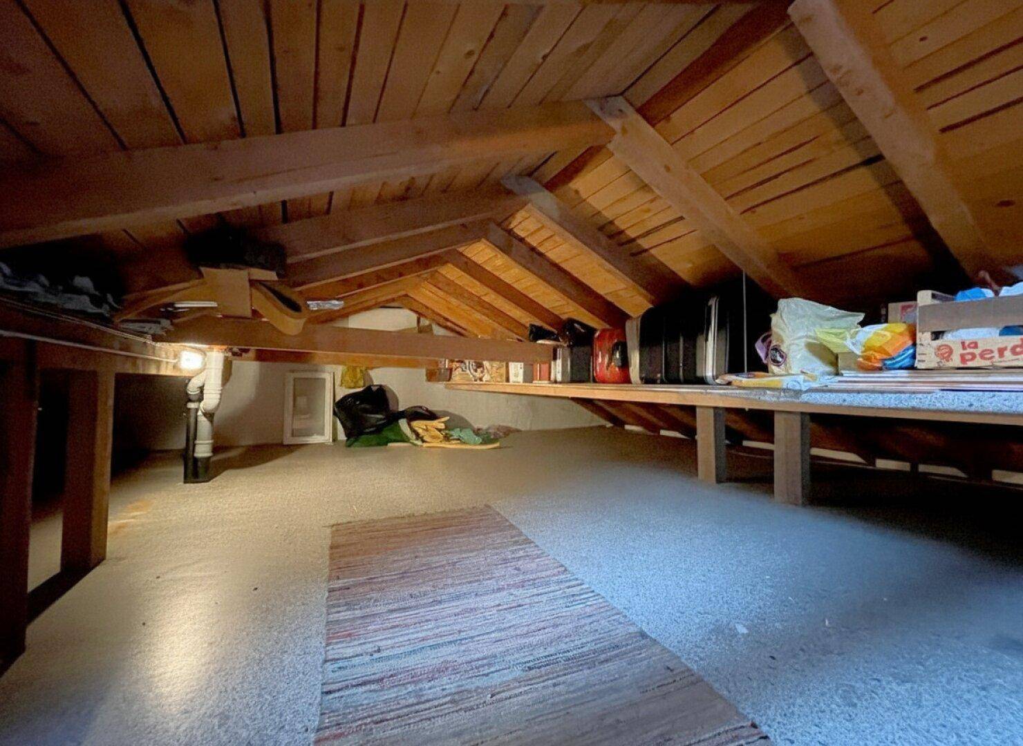 Geräumiger Dachboden mit sichtbaren Holzbalken und viel Stauraum unter dem Dach.