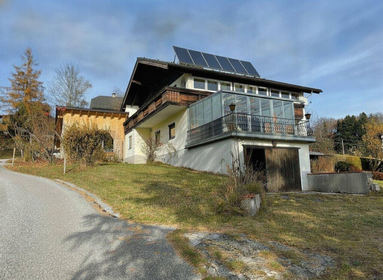 Ansicht des Hauses mit Solaranlage auf dem Dach, Wintergarten und integrierter Garage.