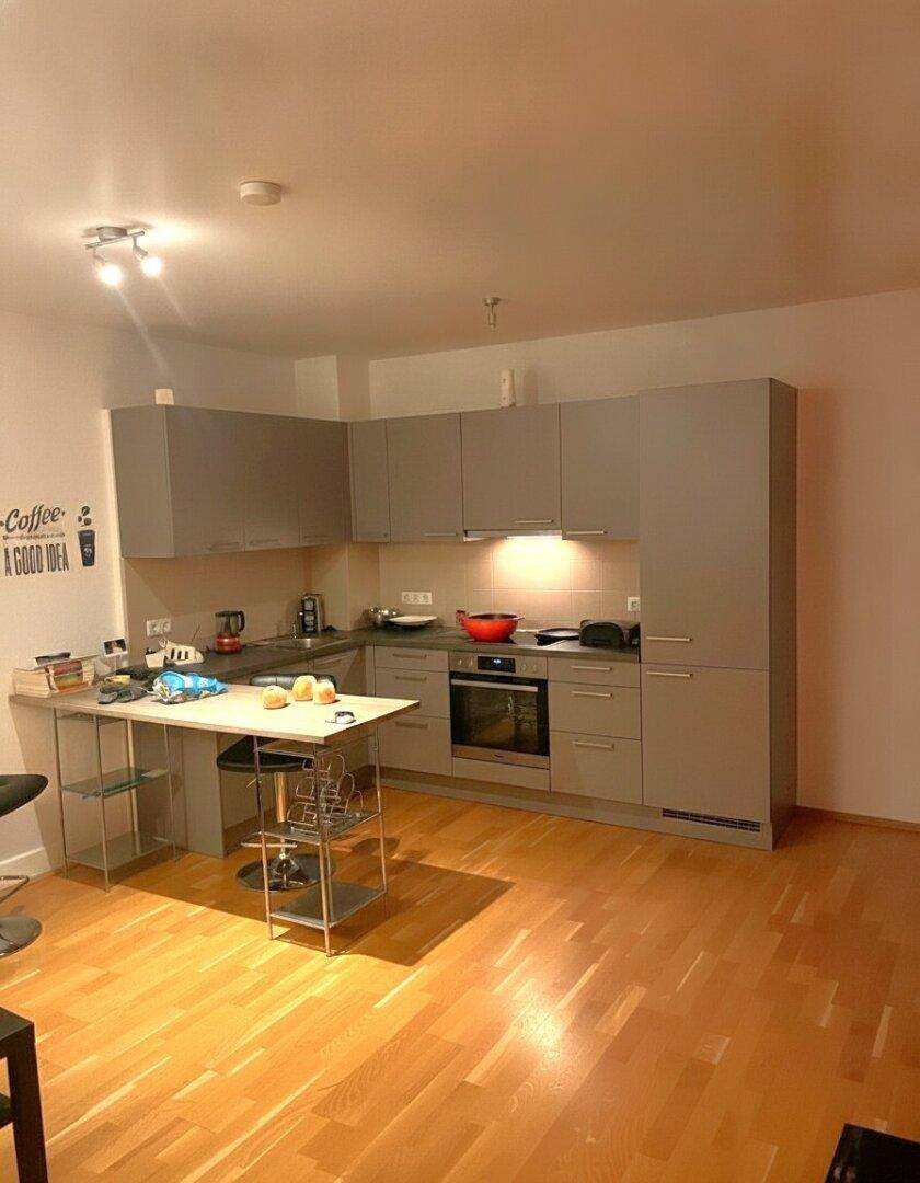 Moderne Küche mit grauen Schränken, Holzboden und einer integrierten Essecke.