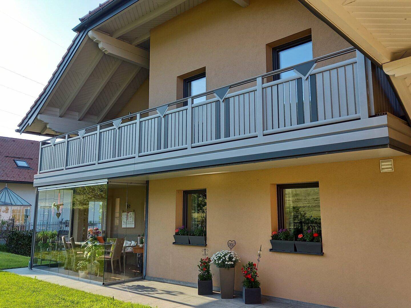 Nahaufnahme der Hausfassade mit Balkon, Blumenkästen und dem verglasten Wintergarten.