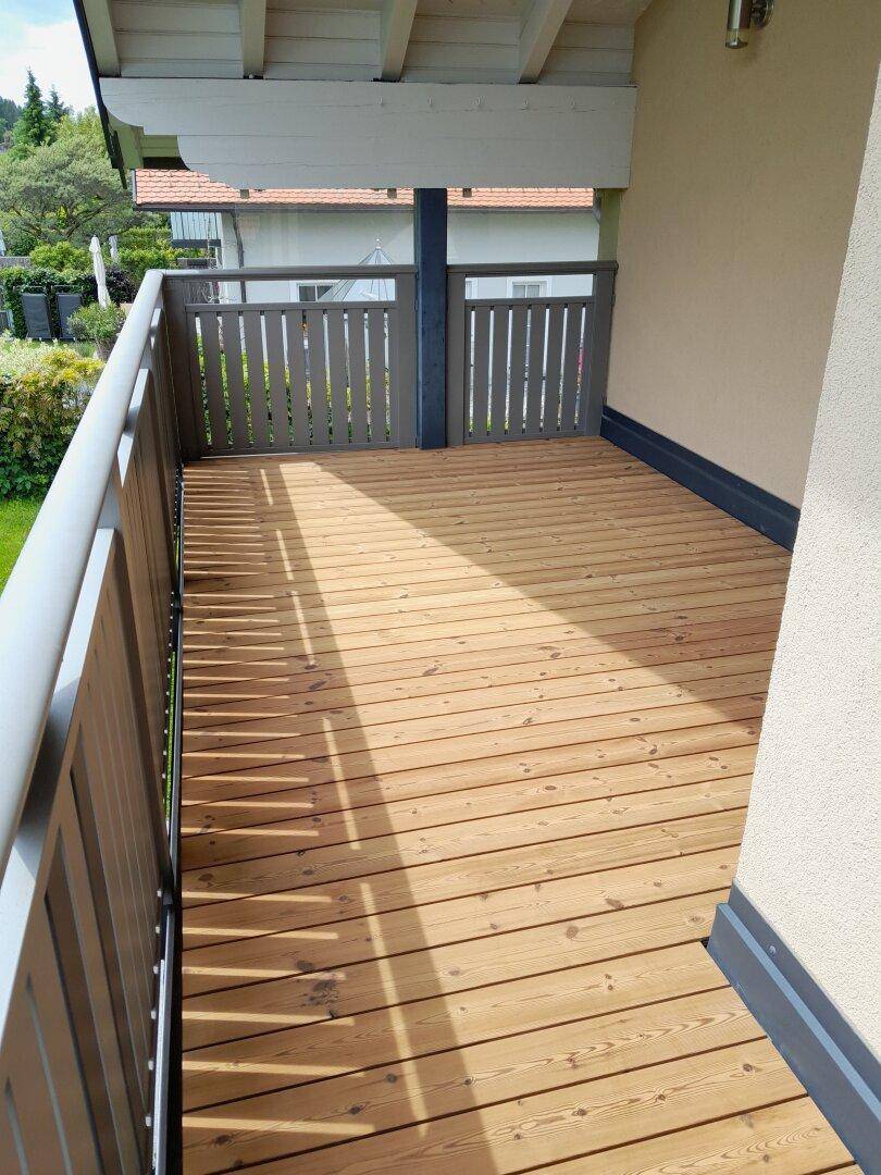 Geräumiger Balkon mit Holzfußboden und stabiler Brüstung, ideal für entspannte Stunden.
