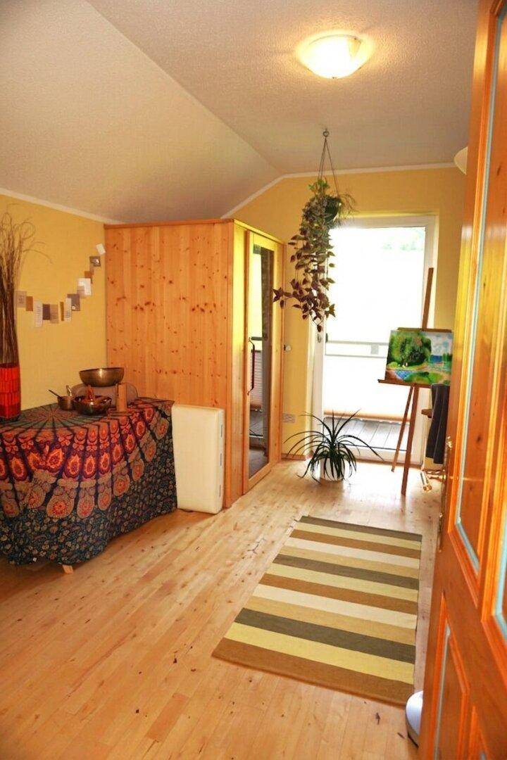 Vielseitiger Raum mit integrierter Sauna, Holzboden und Zugang zu einem Balkon.