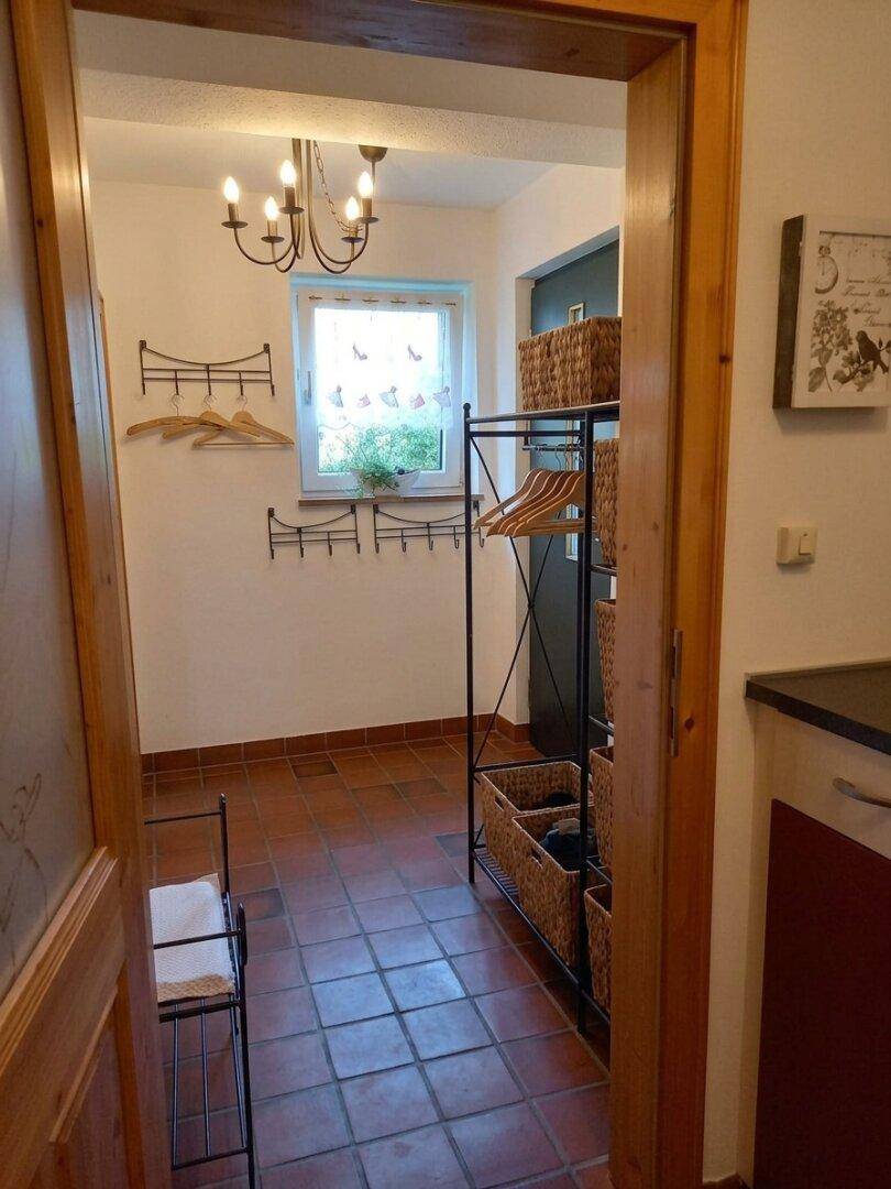 Praktischer Abstellraum mit Terrakottafliesen, Fenster und Aufbewahrungsmöglichkeiten.