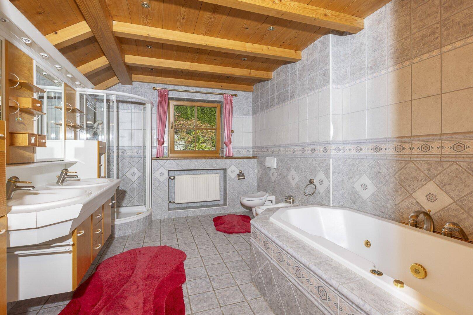 Geräumiges Badezimmer mit Doppelwaschbecken, Badewanne, Dusche und Holzbalkendecke.