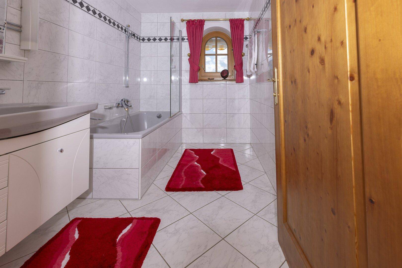 Helles Badezimmer mit Badewanne, Waschbecken und weißen Fliesen.