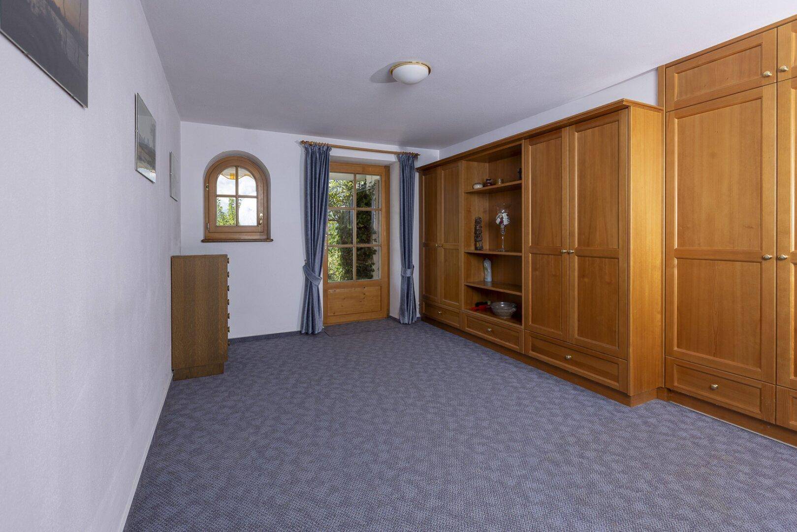 Geräumiges Schlafzimmer mit Teppichboden und großen Holzschränken.