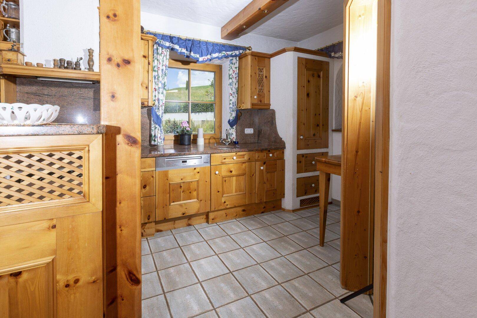 Traditionelle Holzküche mit eingebauten Geräten und einem Fenster mit Blick ins Grüne.