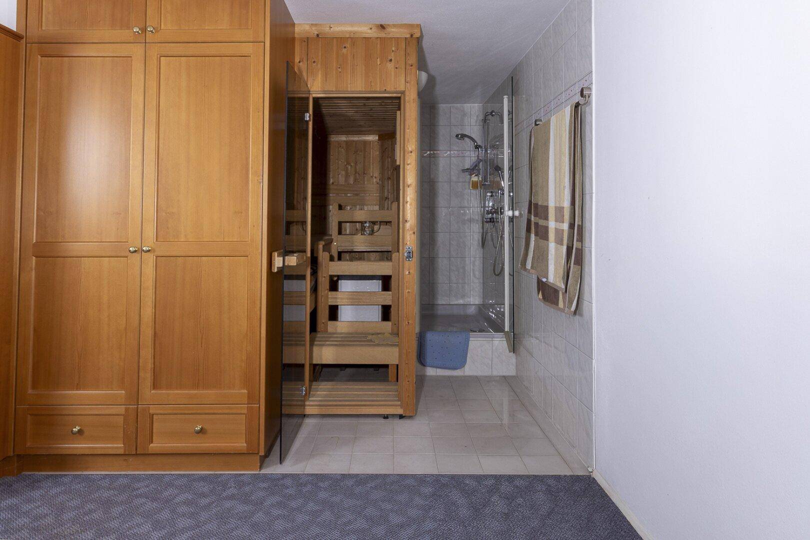 Bereich mit Sauna, Duschkabine und Holzschränken, ideal für Entspannung.