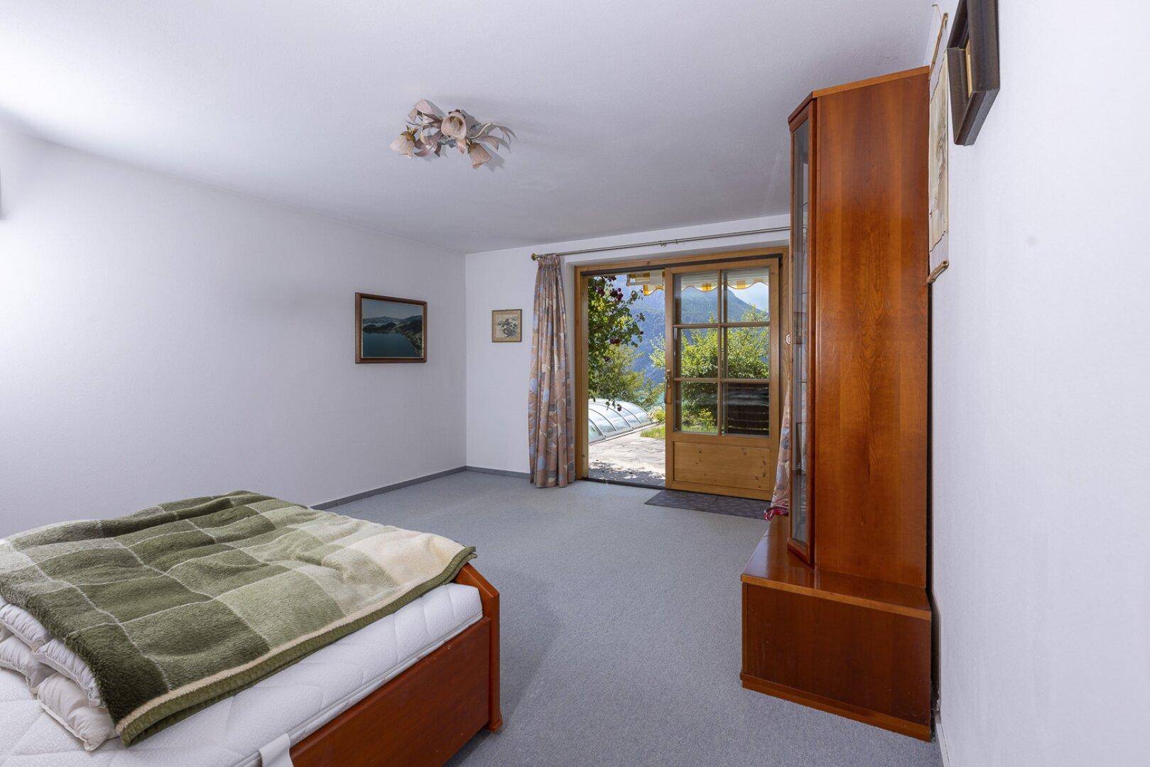 Helles Schlafzimmer mit Teppichboden und Zugang zum Gartenbereich.