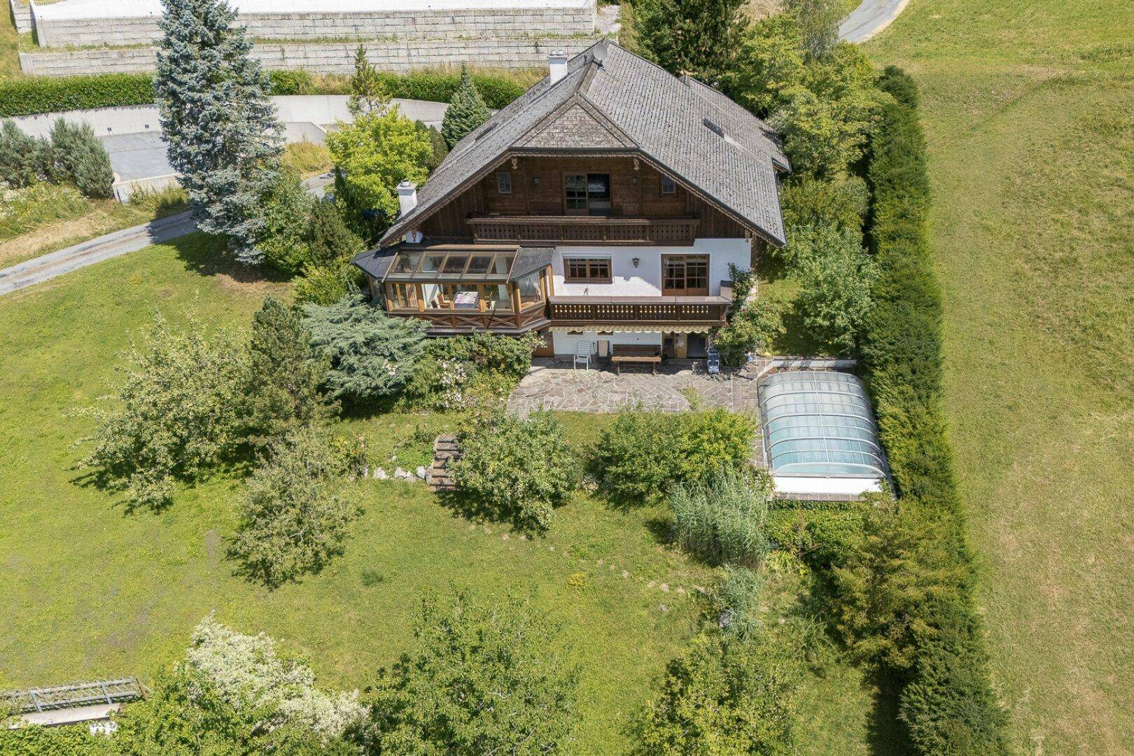 Luftaufnahme des Hauses mit großem Garten, Terrasse und überdachtem Poolbereich.