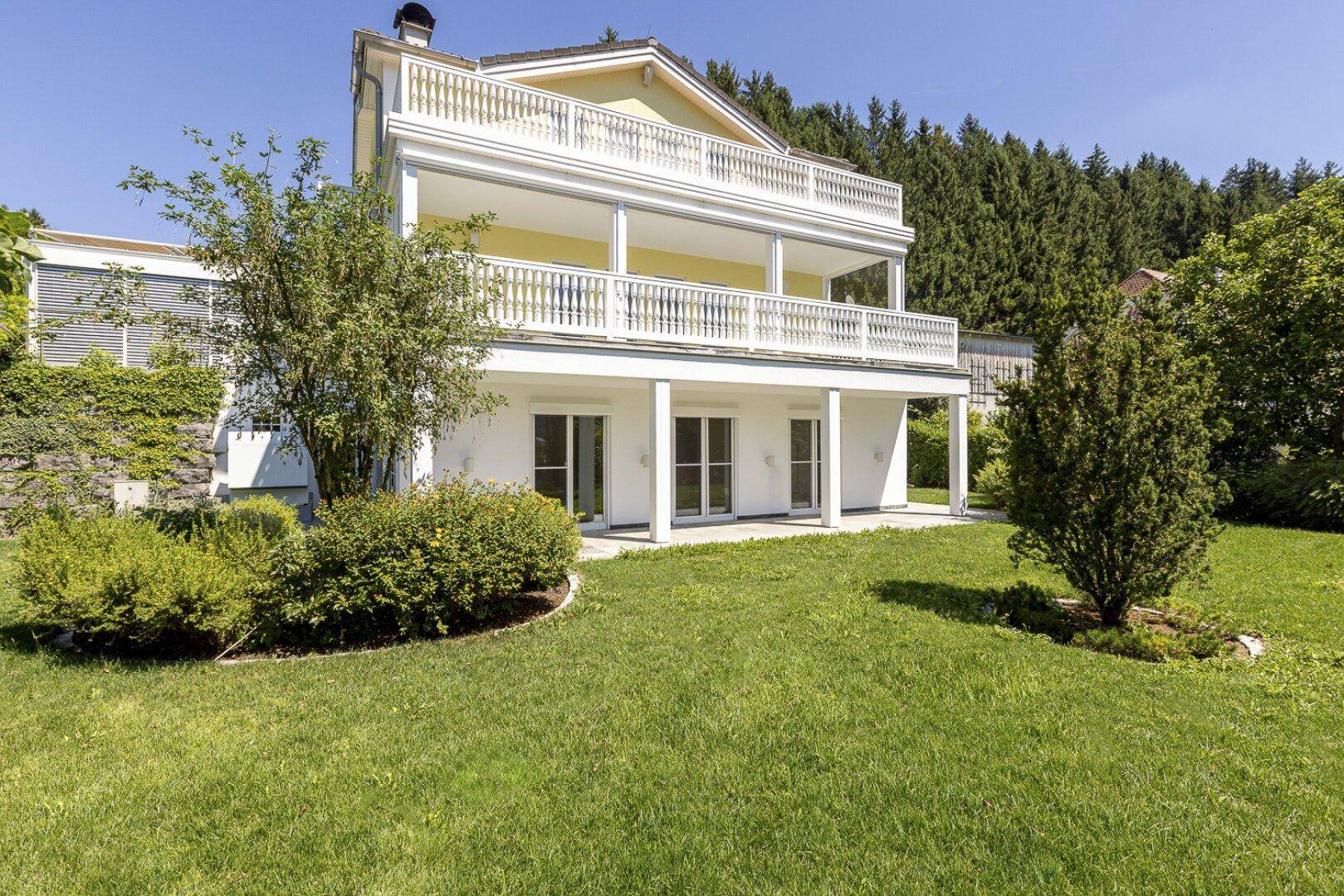 Großzügiger Gartenbereich mit gepflegtem Rasen und Blick auf die helle Fassade des Hauses.