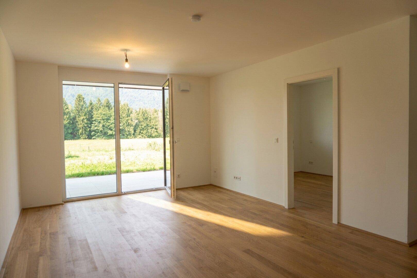 Heller Wohnraum mit Holzfußboden und großen Schiebetüren, die einen direkten Zugang zur Natur bieten.