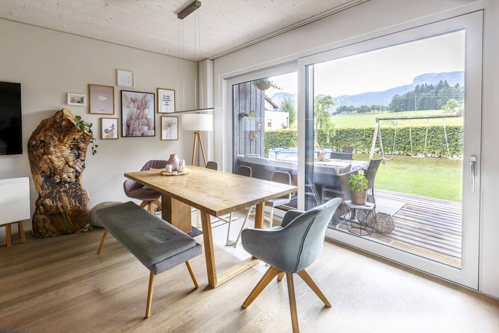 Essbereich mit Holztisch, modernen Stühlen und großem Fenster mit Bergblick.