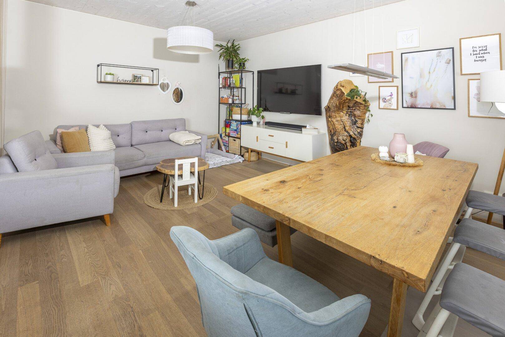 Gemütlicher Wohn- und Essbereich mit Sofa, Holzboden und moderner Dekoration.