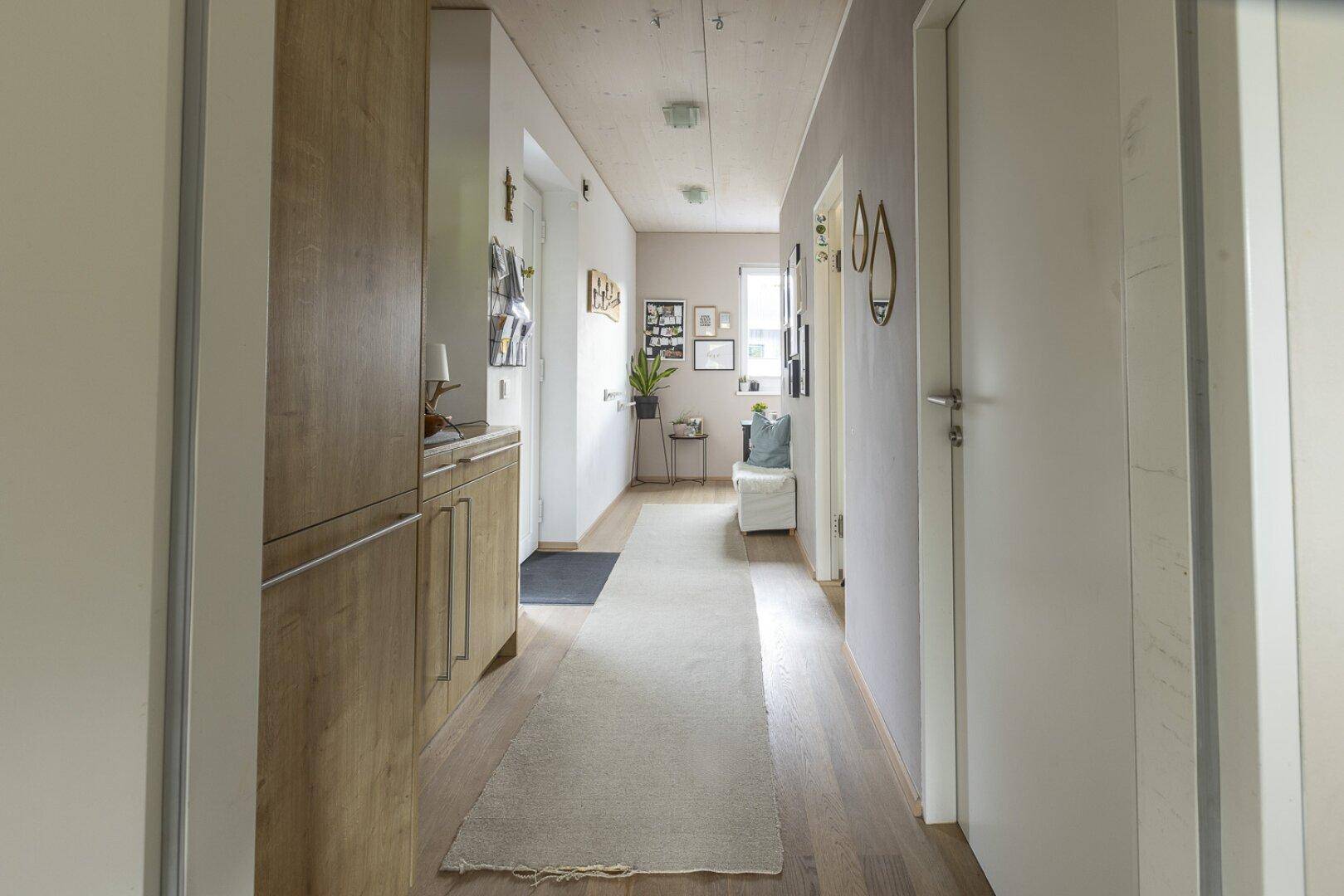 Heller Flur mit Holzboden, Einbauschränken und moderner Wandgestaltung.