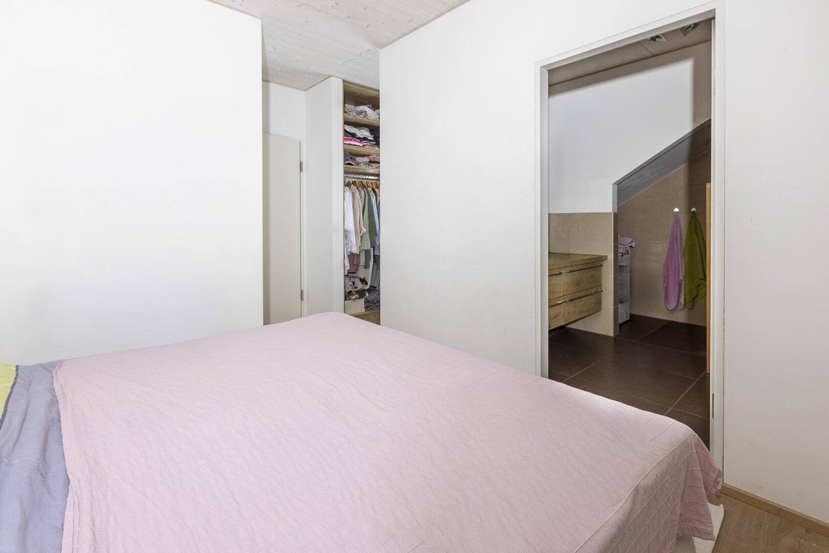 Schlafzimmer mit Doppelbett und Zugang zu einem begehbaren Kleiderschrank.