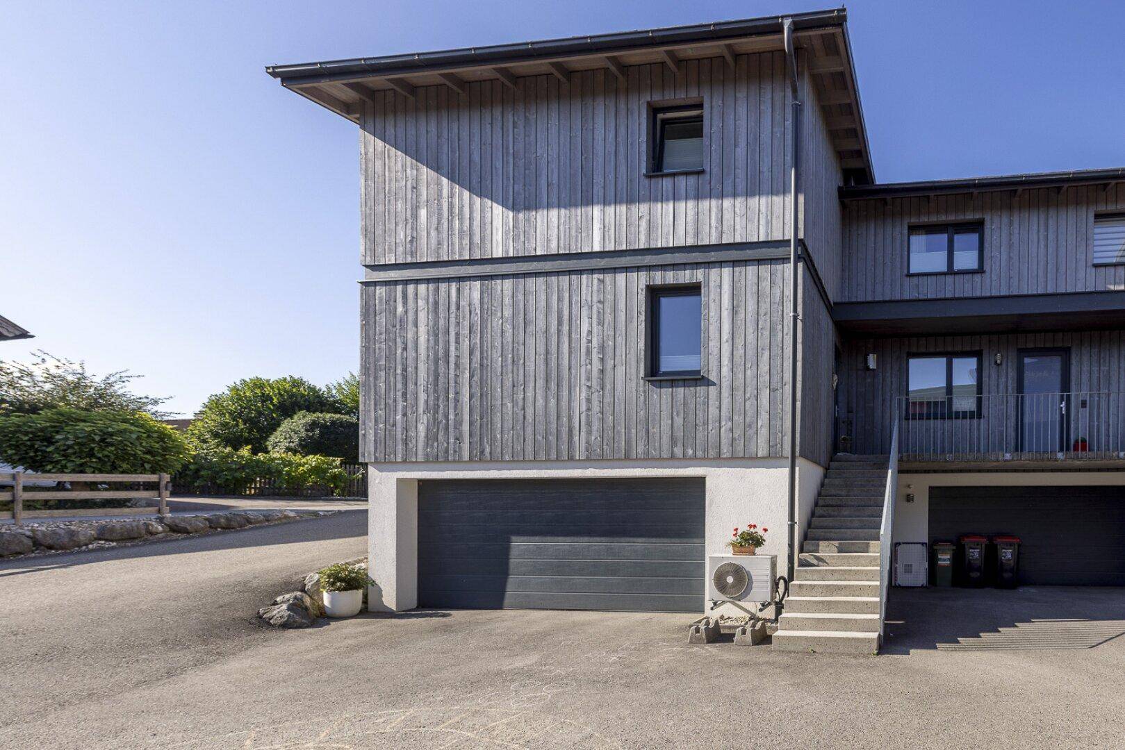 Ansicht der modernen Holzfassade mit Garage und Außentreppe.