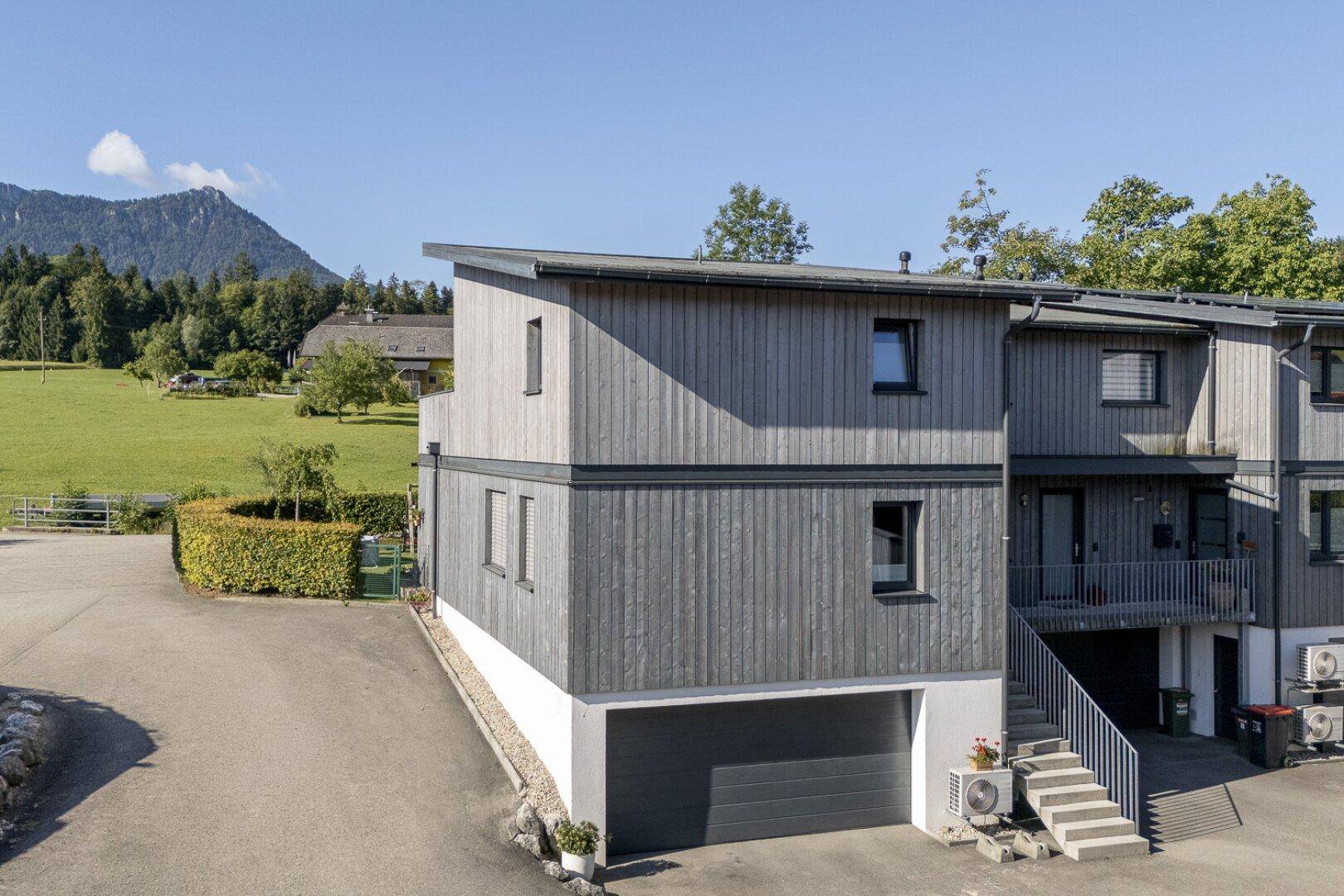 Gesamtansicht der modernen Wohnanlage mit Holzfassade und Bergblick.