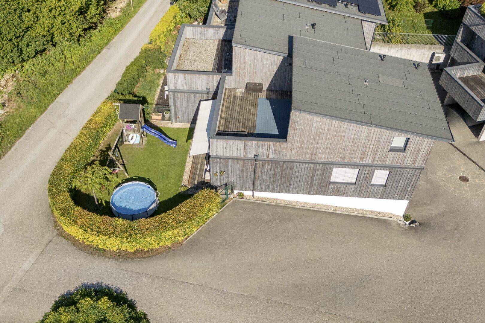 Luftaufnahme des Hauses mit Garten, Pool, Spielplatz und Hecke.