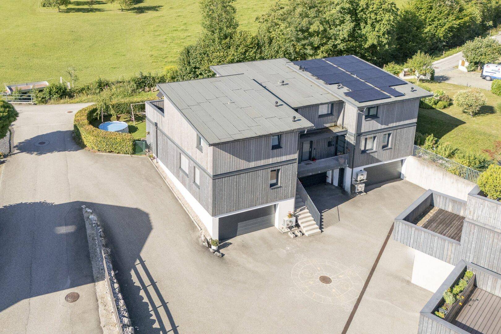 Luftaufnahme der Wohnanlage mit mehreren Einheiten, Solaranlagen und Bergblick.