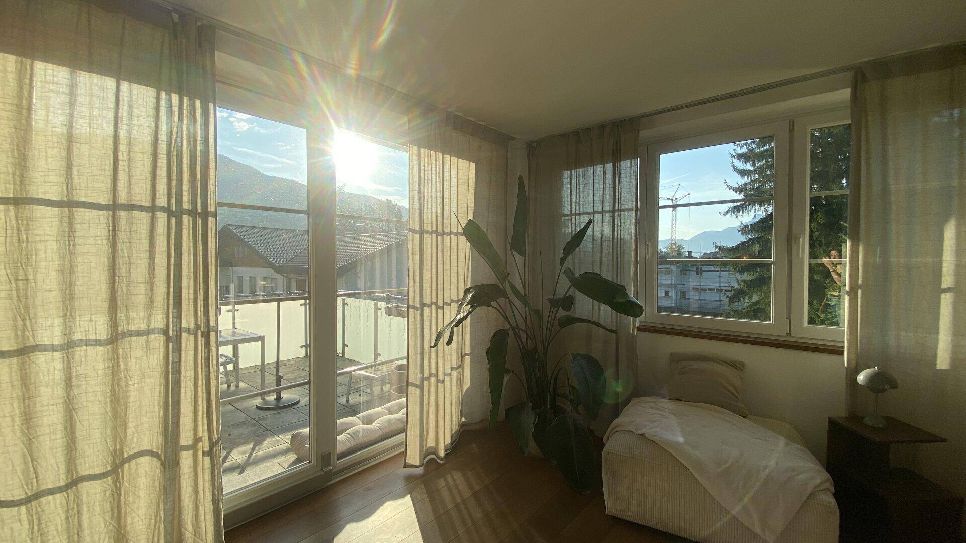 Lichtdurchfluteter Wohnbereich mit großen Fenstern und Blick auf die Berge.