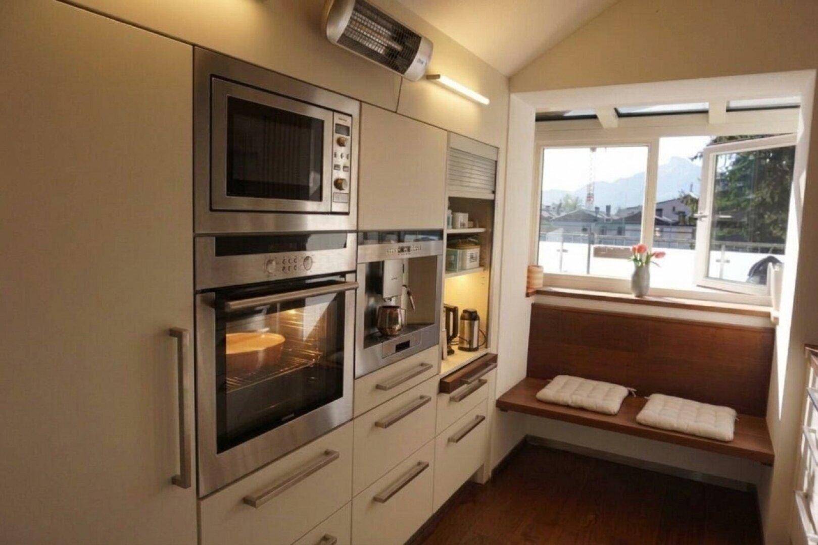 Voll ausgestattete Küche mit integrierten Geräten, Backofen und Mikrowelle.