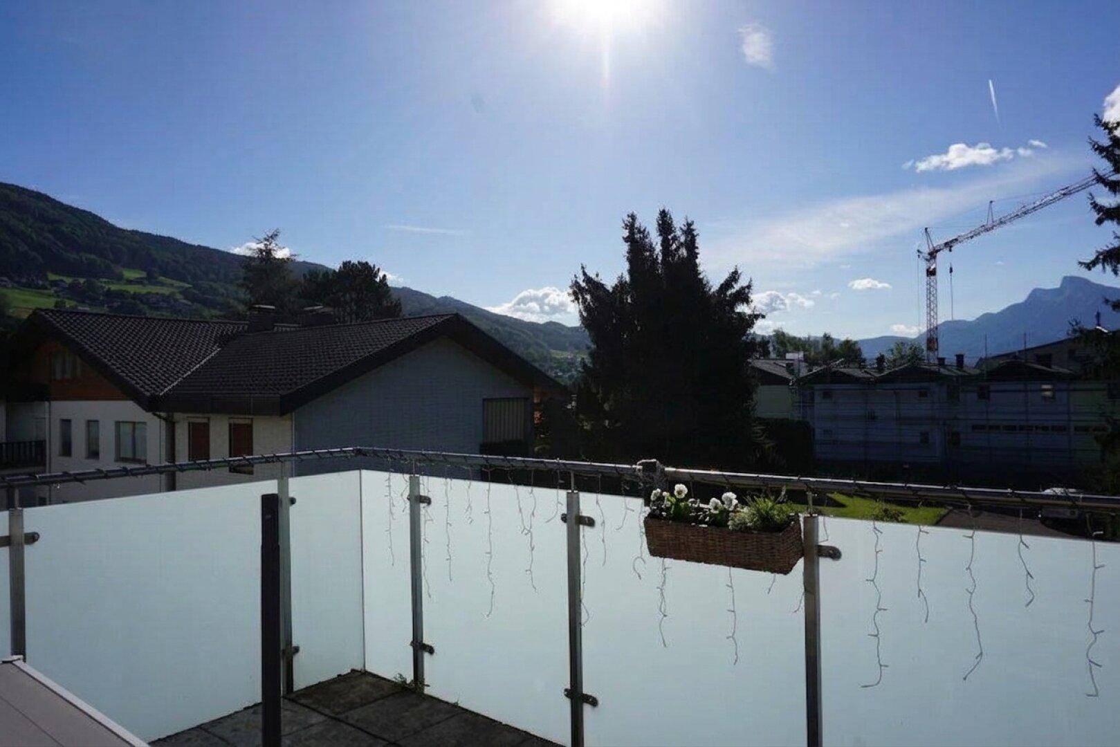 Weitläufiger Blick von der Terrasse auf die Berge und die Umgebung an einem sonnigen Tag.