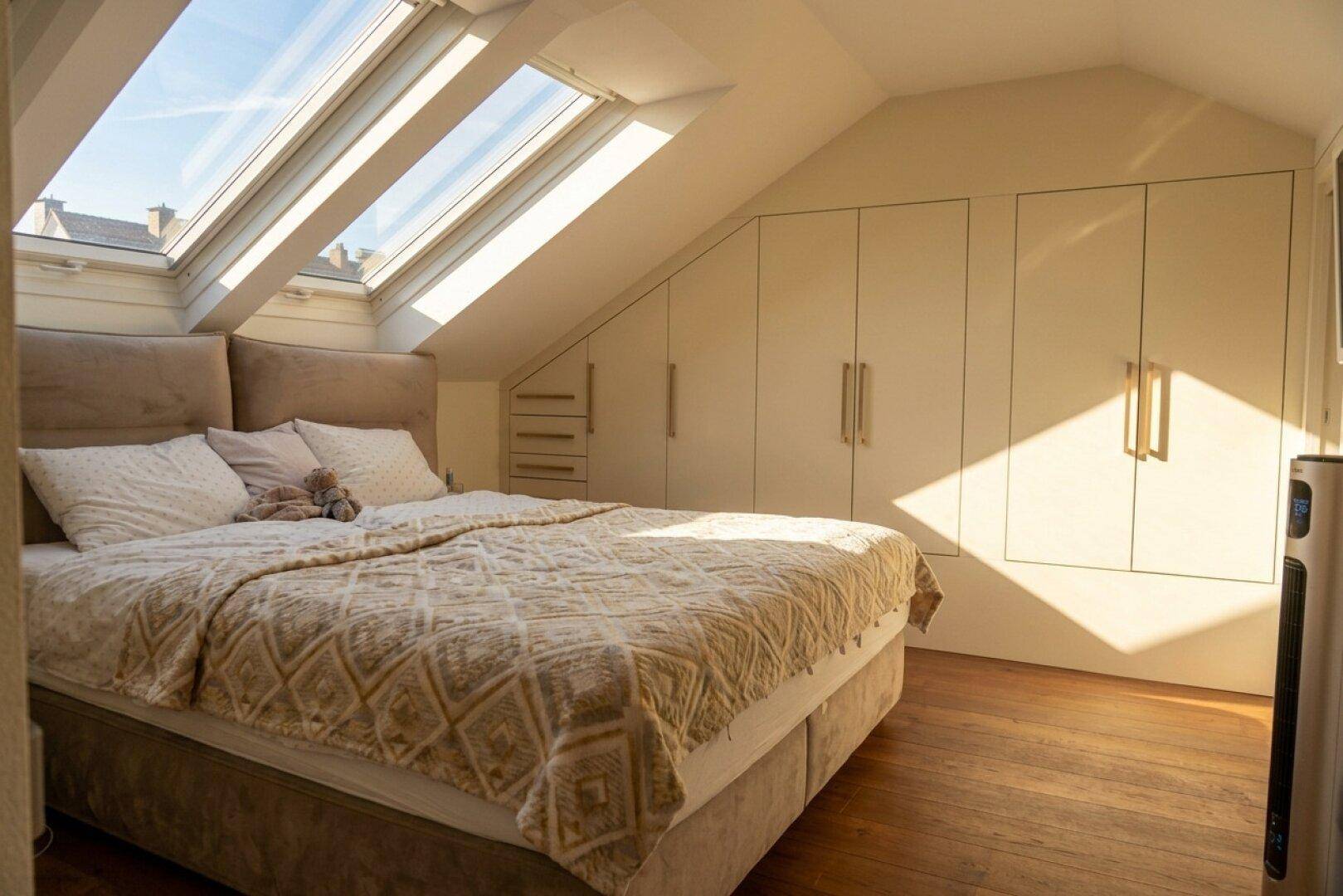Geräumiges Schlafzimmer im Dachgeschoss mit Einbauschränken und viel Tageslicht.
