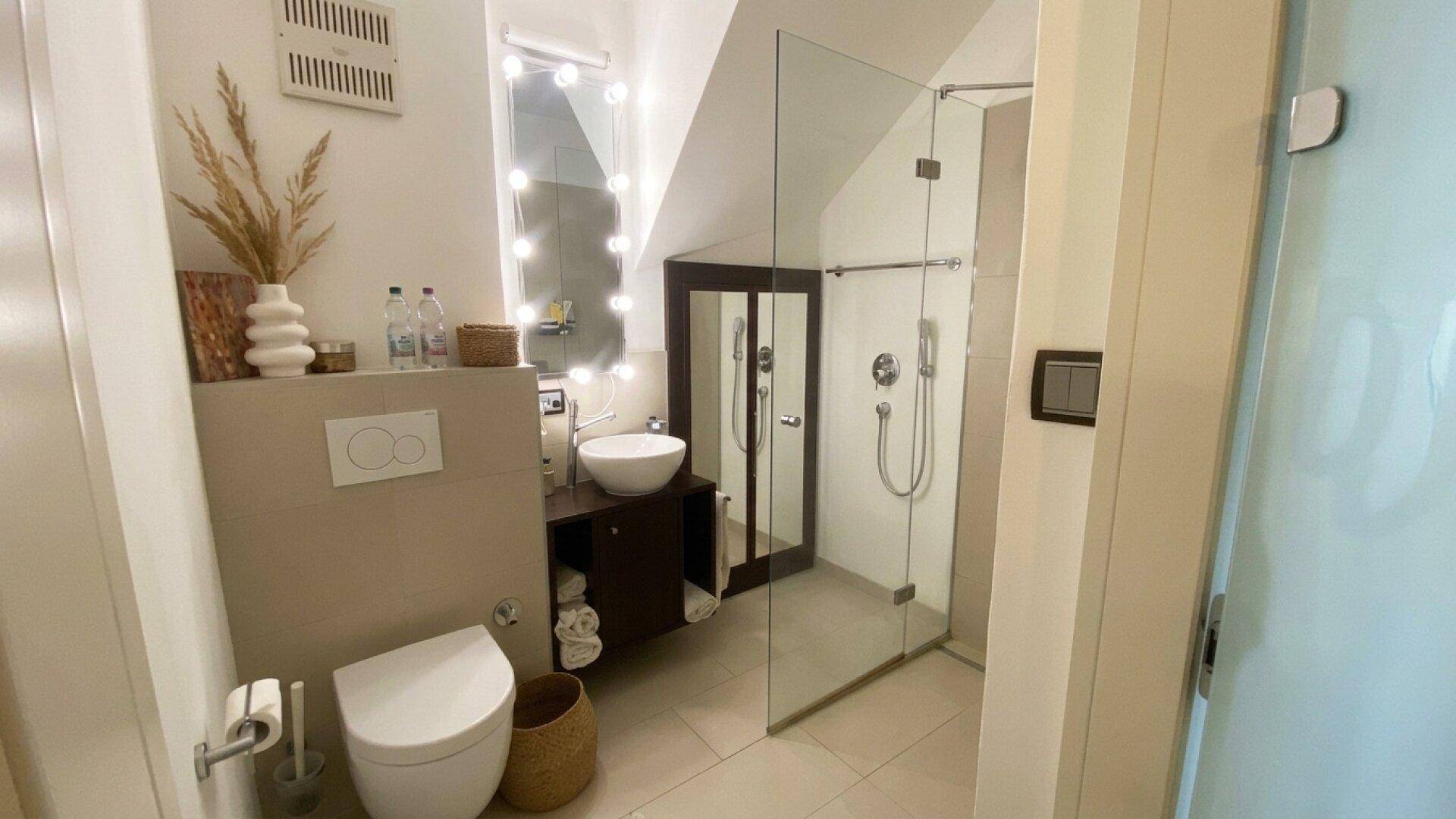 Modernes Badezimmer mit begehbarer Dusche, Waschtisch und Dachschräge.