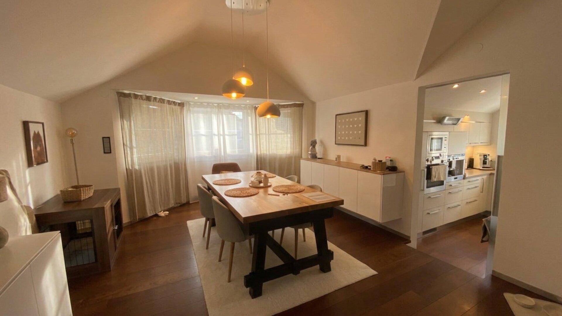 Heller Essbereich mit Holztisch und Zugang zur modernen Küche.