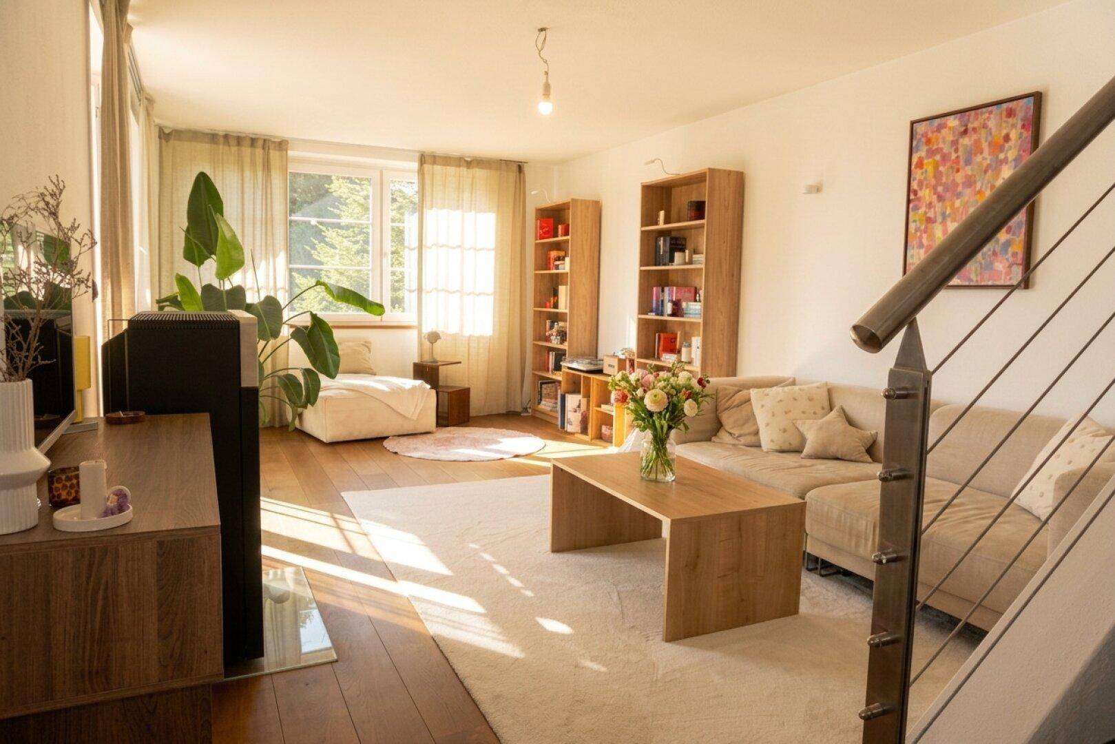 Helles Wohnzimmer mit Holzboden, bequemer Couch und Blick ins Grüne.