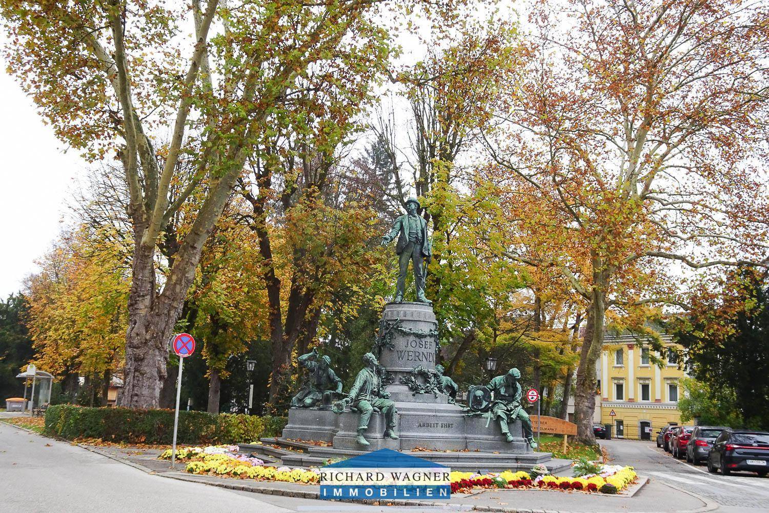 Historisches Denkmal in einer grünen Parkanlage mit herbstlichen Bäumen und Rasenflächen.