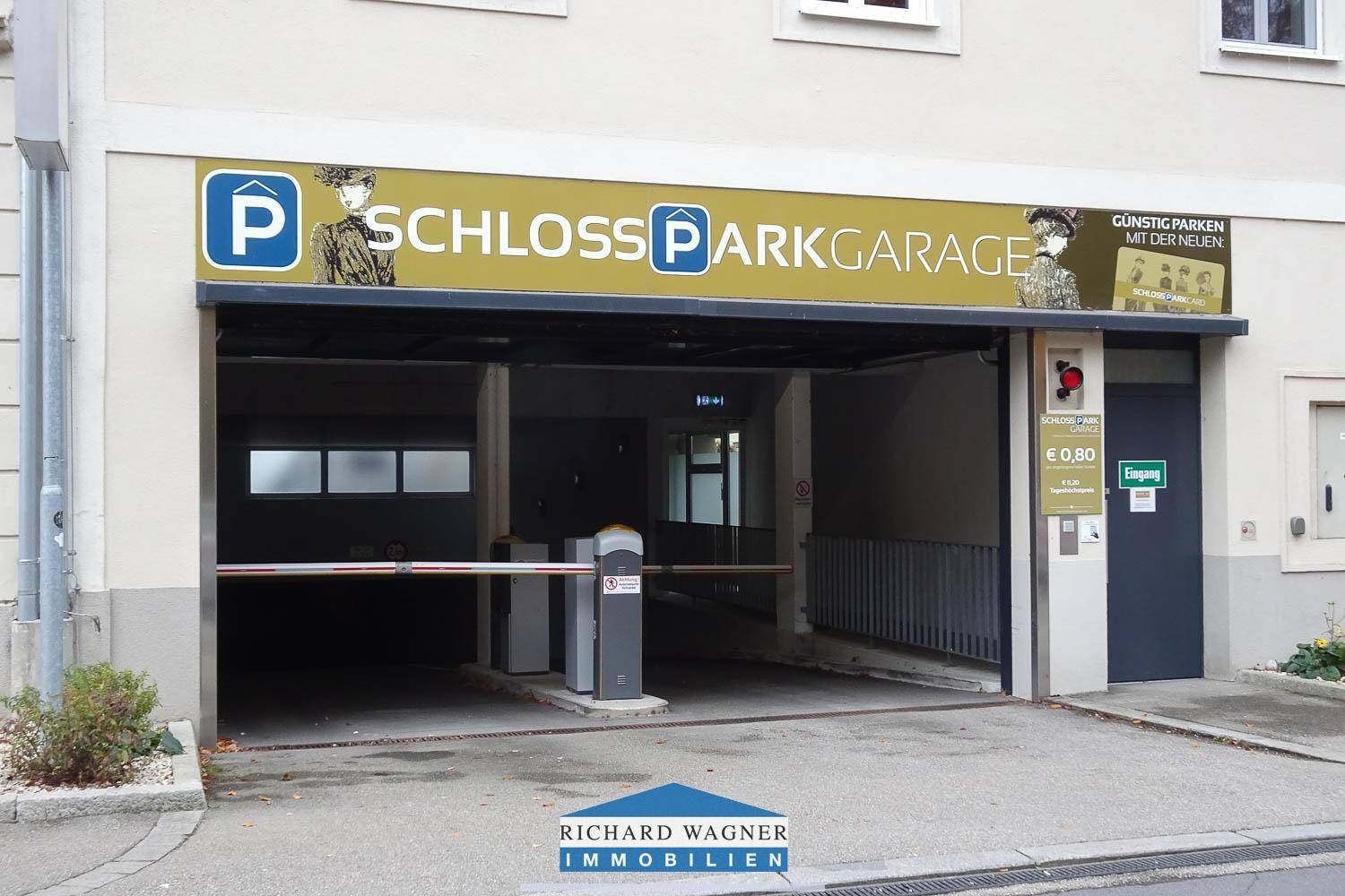 Eingang zur Schloss Parkgarage mit Schranke, Hinweisschildern und leichter Rampe.
