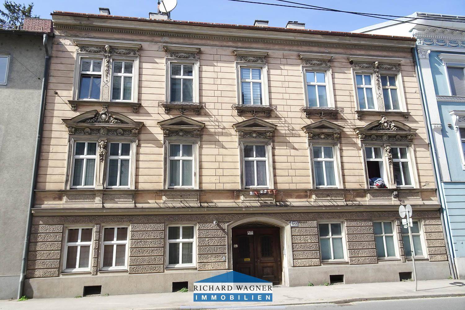 Historische Fassade eines Altbaugebäudes mit reich verzierten Fenstern und klassischer Architektur.