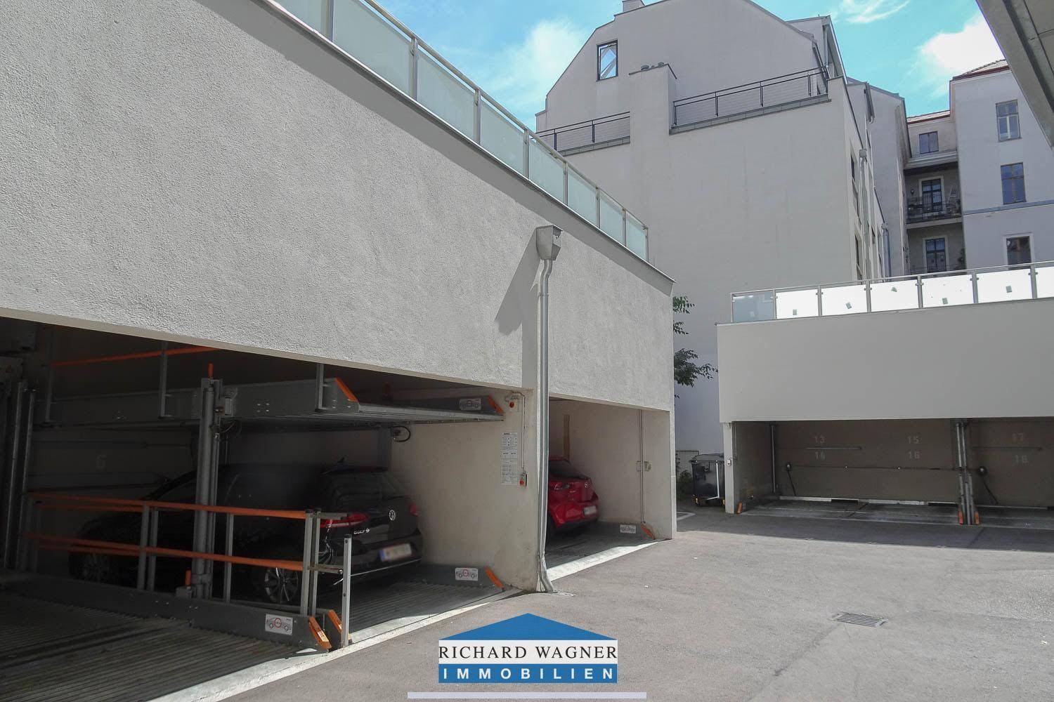 Außenansicht einer Tiefgarage mit mechanischen Parksystemen für mehrere Fahrzeuge in einem modernen Gebäude.