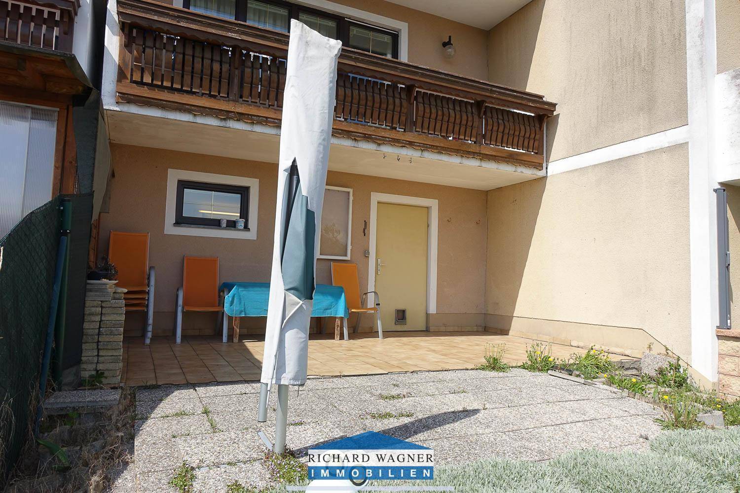 Gemütliche Terrasse mit Gartenmöbeln und Sonnenschirm, ideal für entspannte Stunden im Freien.