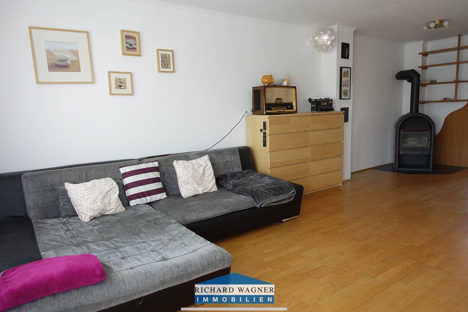 Geräumiges Wohnzimmer mit Sofa, Holzmöbeln und einem charmanten Holzofen.